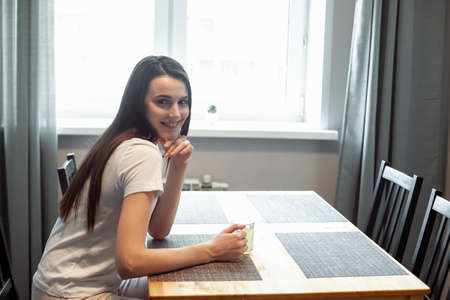 beautiful young woman drinking hot beverage. Attractive girl relaxing at homeの写真素材