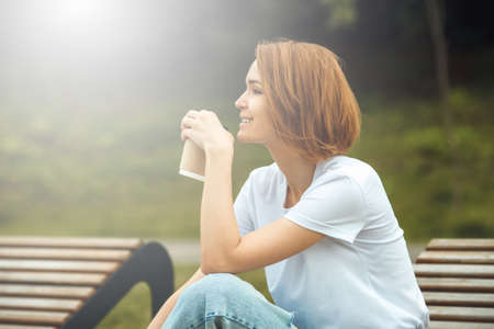 Young city girl with paper coffee cup. Attractive hipster woman with hot drinkの写真素材