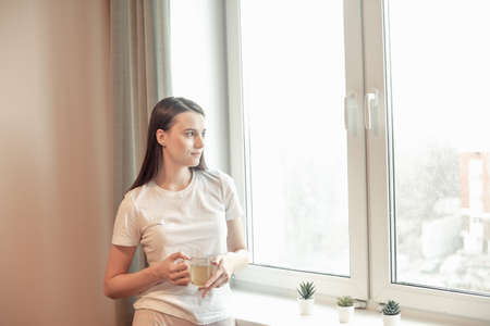 Beautiful woman drinking morning tea behind window. Challenge of a new day. Copy spaceの写真素材