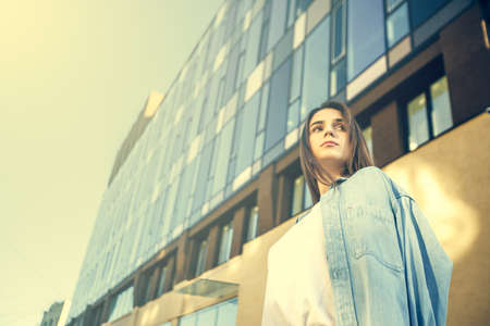 Summer sunny lifestyle fashion portrait. Young stylish hipster woman walking on the street. Summer wear style trendの写真素材