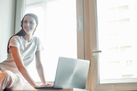 Girl working on computer laptop in light room. Woman chat in social network via net-book in modern interiorの写真素材