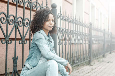 Attractive dark skin girl portrait. City hipster young woman walking on streetの写真素材