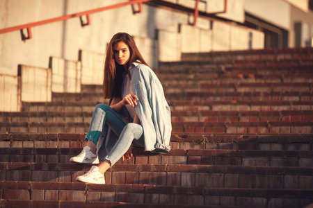 Summer sunny lifestyle fashion portrait. Young stylish hipster woman walking on the street. Summer wear style trendの写真素材