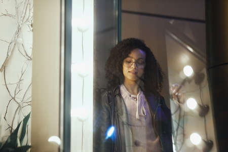 Fashionable woman on urban city street at night. Beautiful african american woman with black curly...