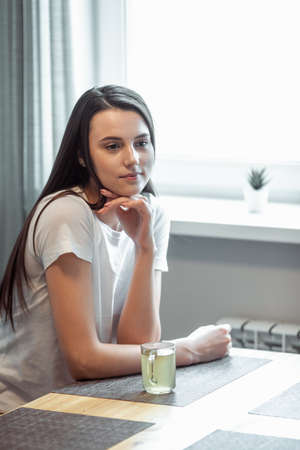 beautiful young woman drinking hot beverage. Attractive girl relaxing at homeの写真素材