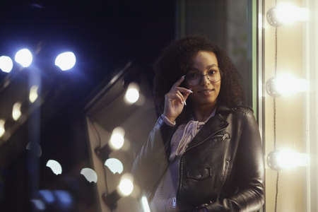 Portrait of young cute curly afro american girl. Night city lights. Neon illuminationの写真素材