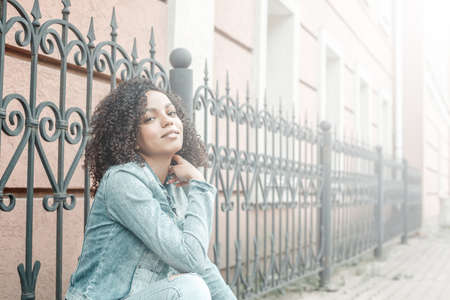 Happy young mulatto girl on sunny city street. Trendy woman portraitの写真素材