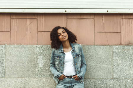 Happy young mulatto girl on sunny city street. Trendy woman portraitの写真素材