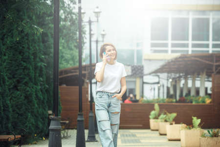 Summer sunny lifestyle fashion portrait. Young stylish hipster woman walking on the street. Summer wear style trendの写真素材