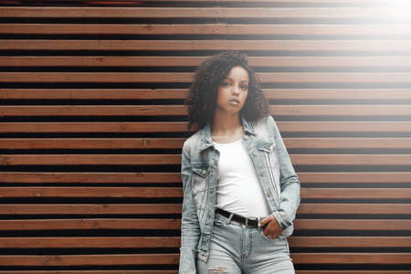 Mulatto black curly girl on street. Sunny summer city. Young woman denim styleの写真素材