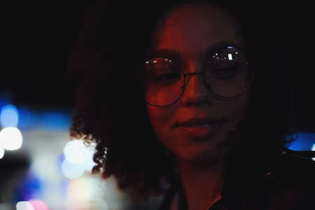 Fashionable woman on urban city street at night. Beautiful african american woman with black curly hairの写真素材