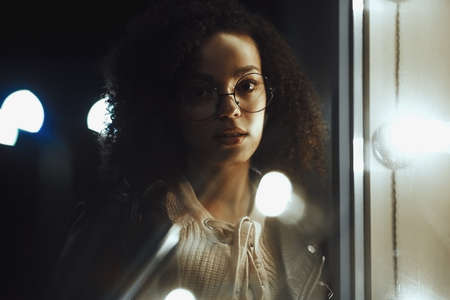 Fashionable woman on urban city street at night. Beautiful african american woman with black curly hairの写真素材