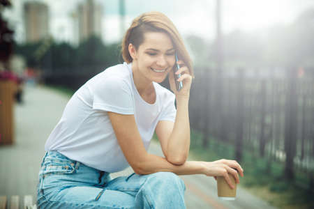 Attractive girl with phone in the street. City portrait of young beautiful woman model. Communication technologyの写真素材