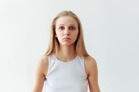 Funny student girl portrait on white background. Grimacing emotion model. Studio portraitの写真素材