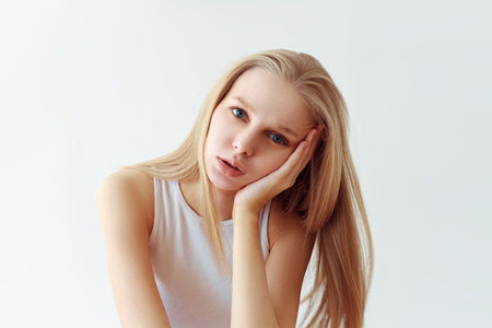 Funny student girl portrait on white background. Grimacing emotion model. Studio portraitの写真素材