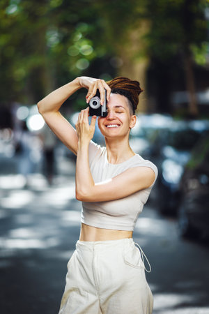 Beautiful happy woman with dreadlocks taking photos with vintage retro film camera. Traveling and photographing conceptの写真素材