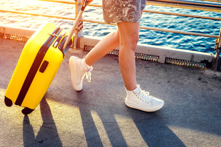 Woman walks around the city carrying a yellow suitcase. Tourist travelingの写真素材