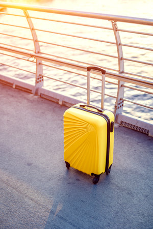 Yellow suitcase on street with sunset sunlight. Tourism mock up. Copy space for your textの写真素材