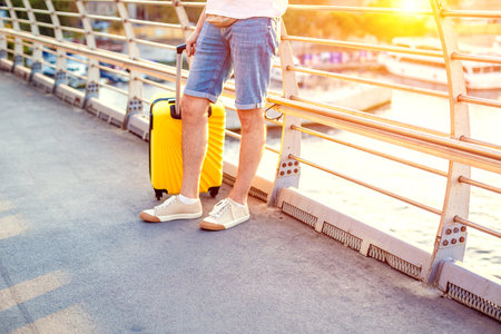 Travel man walking with yellow suitcase walking through the cityの写真素材