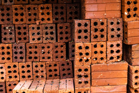 Stack of red clay bricks with holes for construction projects.の写真素材