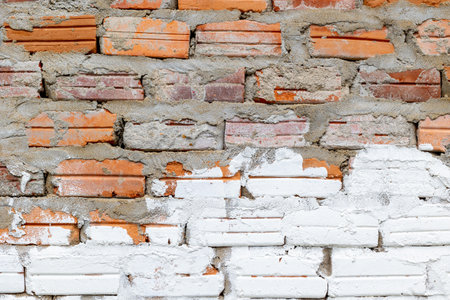 Rustic brick wall with weathered red and white paint texture.の写真素材