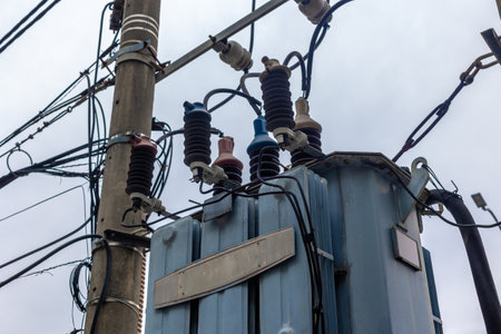 Electrical transformer on utility pole with insulators and cables.の写真素材