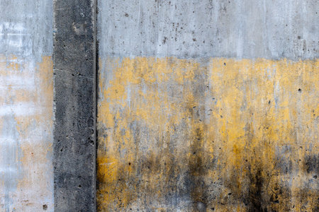 Weathered concrete wall with yellow and gray textures.の写真素材