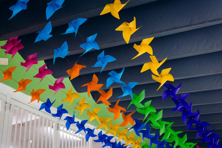 Colorful hanging pinwheels under ceiling with bright blue, orange, green, and pink decorations.