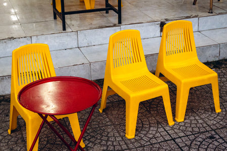 Vibrant yellow plastic chairs and red table in outdoor setting.の写真素材