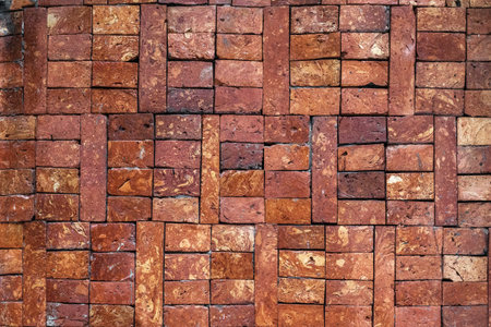 Rustic red brick wall with varied square patterns for architectural design.