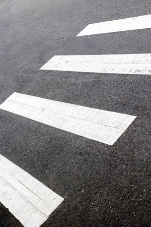 Urban crosswalk with white stripes on asphalt street surface.の写真素材