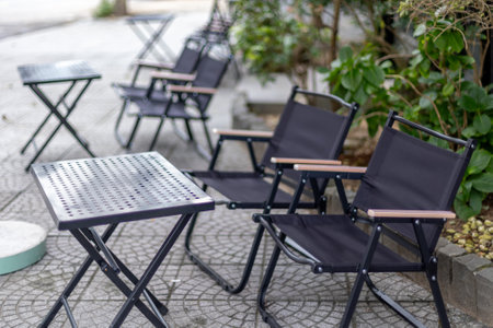 Outdoor black folding chairs and tables on stone patio.の写真素材