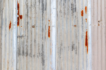 Weathered rusty metal sheet with vertical corrugated texture and patina.の写真素材