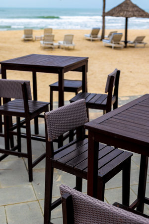 Tropical beachfront bar with empty chairs and tables by the sea.