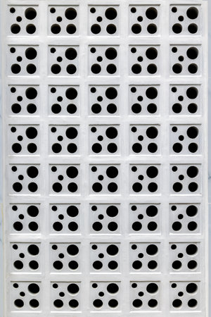 Geometric pattern of white perforated blocks with circular holes.