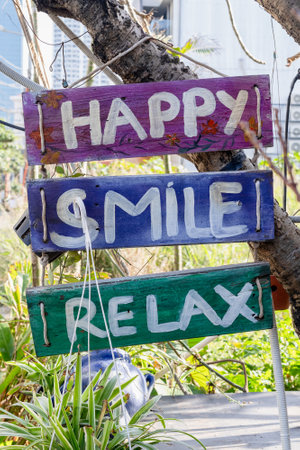 Colorful wooden signs with positive messages hanging outdoors in sunny garden.の写真素材