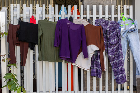 Casual clothes hanging on fence for air drying outdoors.の写真素材