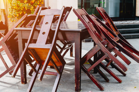 Wooden chairs stacked on table outdoors in sunlight.の写真素材