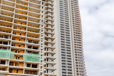 Urban construction site with high-rise buildings under cloudy sky.