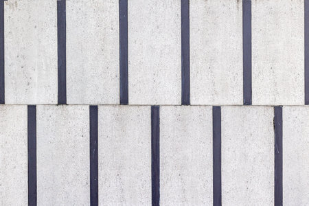 Gray concrete wall with vertical black stripes creating geometric pattern.