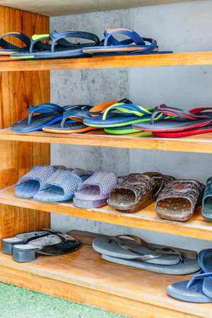 Colorful assortment of flip flops and shoes on wooden shelves.