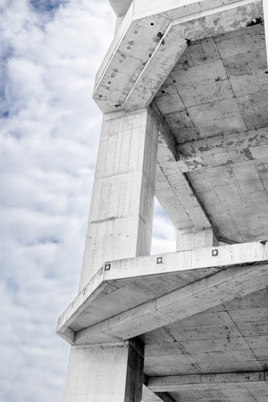 Abstract view of unfinished concrete building against cloudy sky.