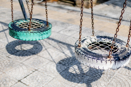Colorful tire swings hanging in park playground on sunny day.