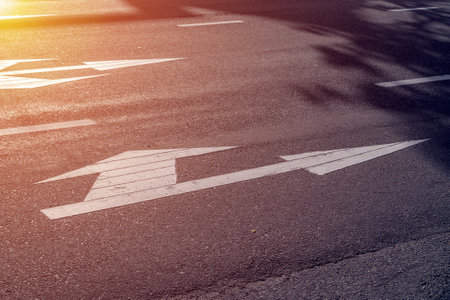 Road intersection with arrow markings at sunset.の写真素材