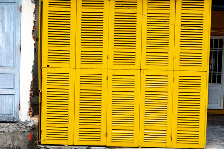Bright yellow wooden shutters on urban building exterior.の写真素材