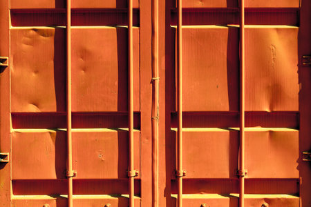Rusty orange freight container doors with vertical bars and weathered surface.