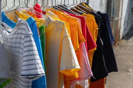 Colorful t-shirts hanging on a clothesline outdoors in sunlight.の写真素材