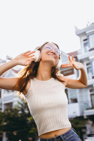 Joyful young caucasian female enjoying music outdoors with headphones.の写真素材