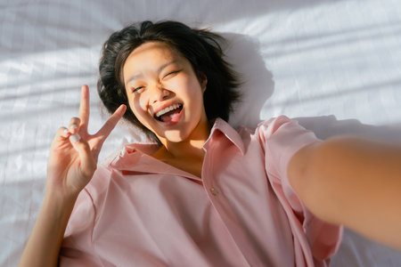 Asian young female smiling and taking a selfie on a sunny day.の写真素材