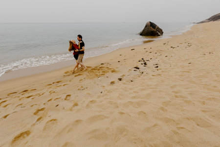Young caucasian couple enjoying a walk on a sandy beach.の写真素材